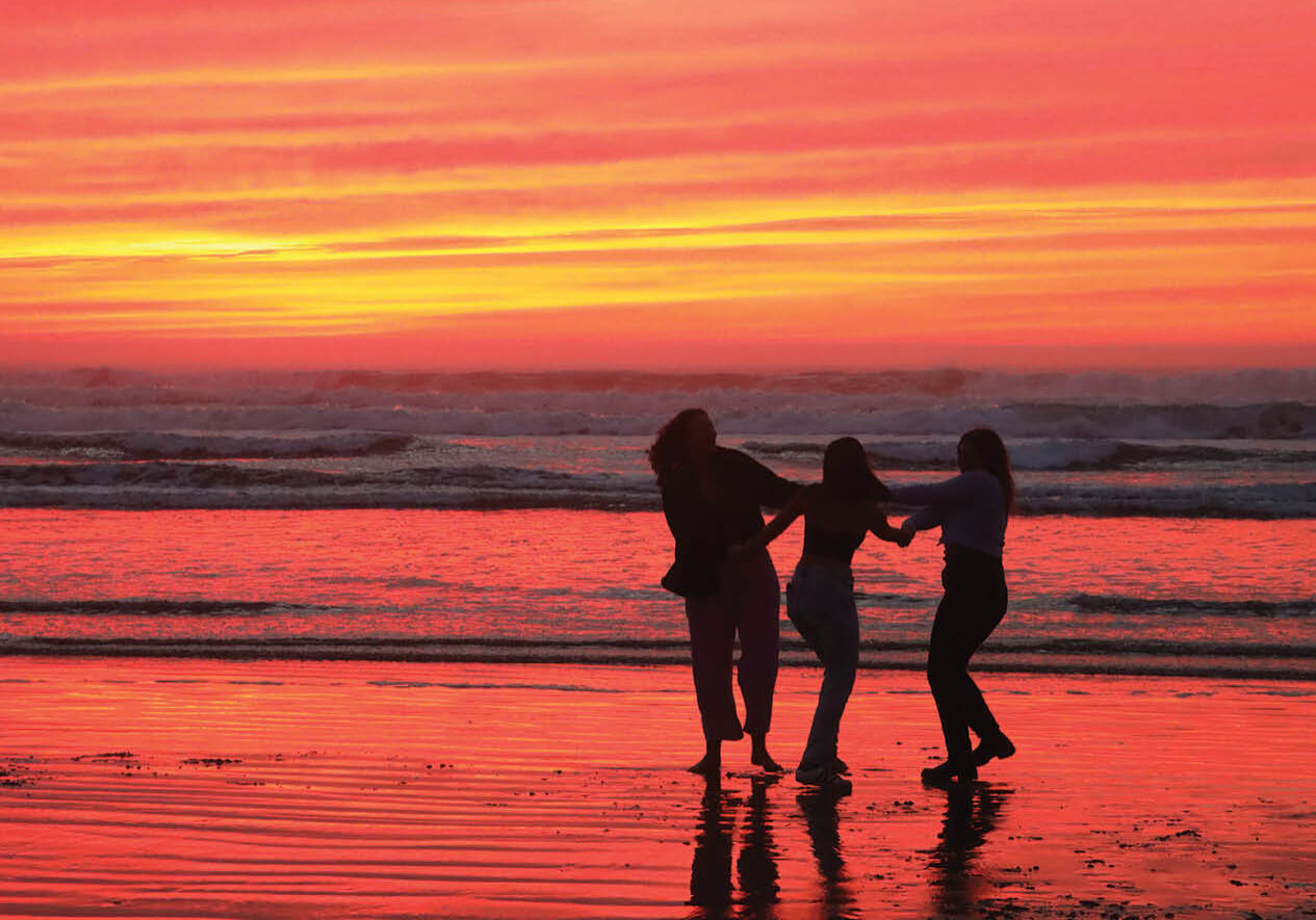 Women dancing on a beach at sunset